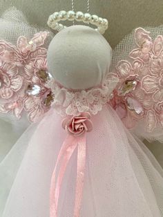 an angel doll with pink flowers and pearls