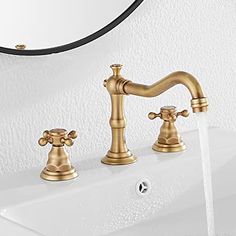 two faucets are shown in front of a white wall and sink with gold fixtures