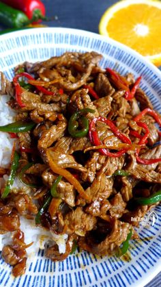 a close up of a plate of food with rice and meat on it next to an orange slice