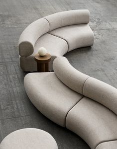 the curved couch is next to a round table