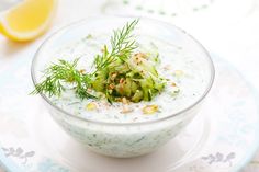 a bowl filled with cucumbers and garnish on top of a table