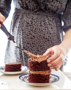 a woman cutting into a piece of chocolate cake