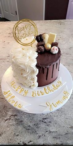 a chocolate cake with white frosting and gold lettering on the top that says happy birthday