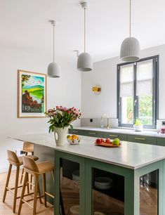 a kitchen with green cabinets and an island in front of a window that has flowers on it