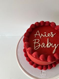 a red cake with the words alex's baby on it sitting on top of a white plate