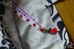 a red, white and blue lanyard with ladybugs on it sitting on top of a table