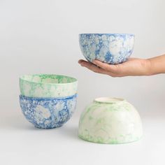 two bowls being held in front of each other with one bowl on it's side