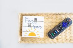 a remote control sitting on top of a wicker tray next to a sign that says fun in the sun