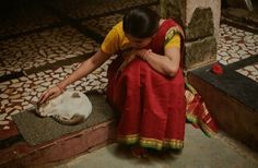 a woman sitting on the ground petting a cat