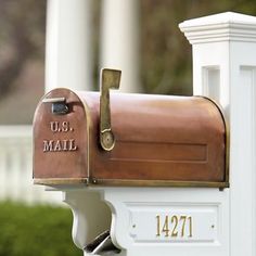 a close up of a mailbox on the side of a white building with trees in the background