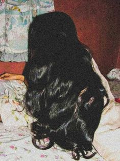 the back of a woman's head laying on a bed with her hair curled up