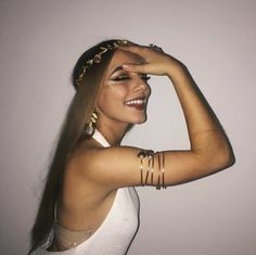 a woman with long hair wearing gold jewelry and bracelets on her head, posing for the camera