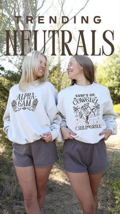 two women wearing matching sweatshirts with the words, trending neutrals on them