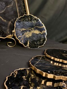 three black and gold plates sitting on top of a table next to a mirror,