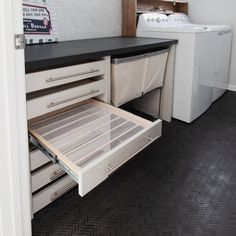 an open drawer in a kitchen next to a washer and dryer