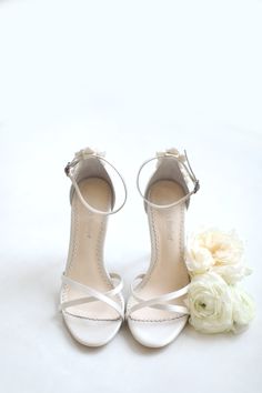 a pair of white shoes with flowers on the floor in front of a white background