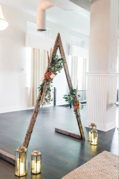 a wedding arch decorated with greenery and candles in front of the entrance to the reception room