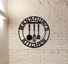 a sign on the wall that says mansour's kitchen with cooking utensils and spoons