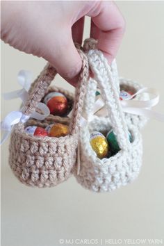 someone is holding two crocheted baskets with candy in them and one has a bow on it