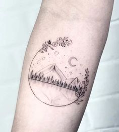 a small tattoo on the arm of a person with mountains and trees in the background