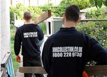 two men in black shirts are standing on stairs outside with their back to the camera