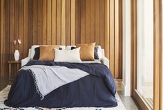 a bed with pillows and blankets on it in front of wood paneled walling