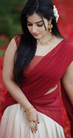 a woman in a red and white sari with her hands on her hips, looking down