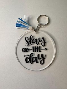 a keychain that says slay the day with an arrow and tassel