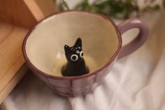 a small black dog sitting inside of a coffee cup