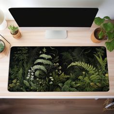 a desk with a computer and plants on it