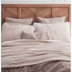 an unmade bed with two pillows on top of it and a wooden headboard