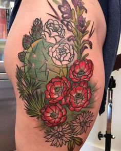 a woman's thigh with flowers and leaves on the bottom part of her leg