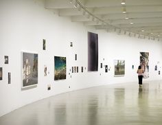 a woman is walking through an art gallery with paintings on the walls and in front of her