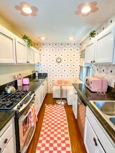 a kitchen with white cabinets and black counter tops next to a pink checkered rug