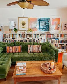 a living room filled with green couches next to a book shelf full of books