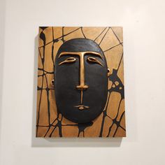 a piece of art that looks like a face is on display in a white wall