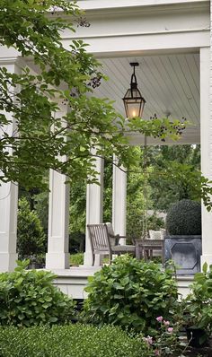 an outdoor patio with chairs and table surrounded by greenery on either side of the porch