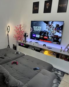 a flat screen tv sitting on top of a white wall in a living room next to a couch