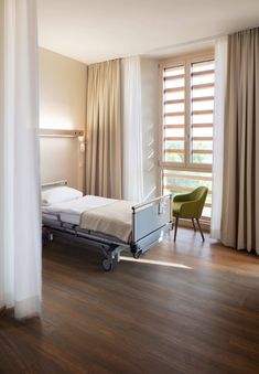 a hospital room with a bed, chair and window