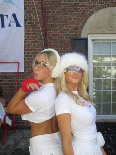 two women dressed in white posing for the camera with santa hats and sunglasses on their heads