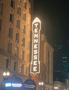 a tall building with a neon sign on it's side in the city at night