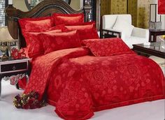 a bed with red comforters and pillows in a living room next to a mirror