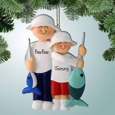 an ornament shaped like two people holding fishing rods and fish, hanging from a christmas tree