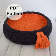 an orange and black crochet dog bed with tassels on the bottom