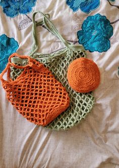 two crocheted bags sitting on top of a bed next to an orange ball