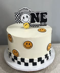 a birthday cake decorated with smiley faces and checkerboard design on the bottom layer