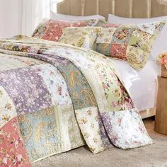 a large bed covered in lots of colorful quilts and pillows on top of it