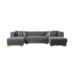 a gray sectional couch with pillows on it's back and side ends, in front of a white background