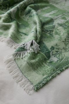 a green and white blanket laying on top of a bed