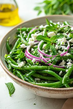 a bowl filled with green beans, onions and feta cheese on top of it